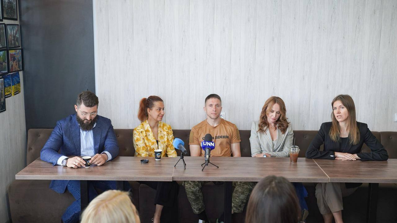 П'ятеро людей сидять за столом, перед ними стоять мікрофони мікрофони з логотипами телеканалів